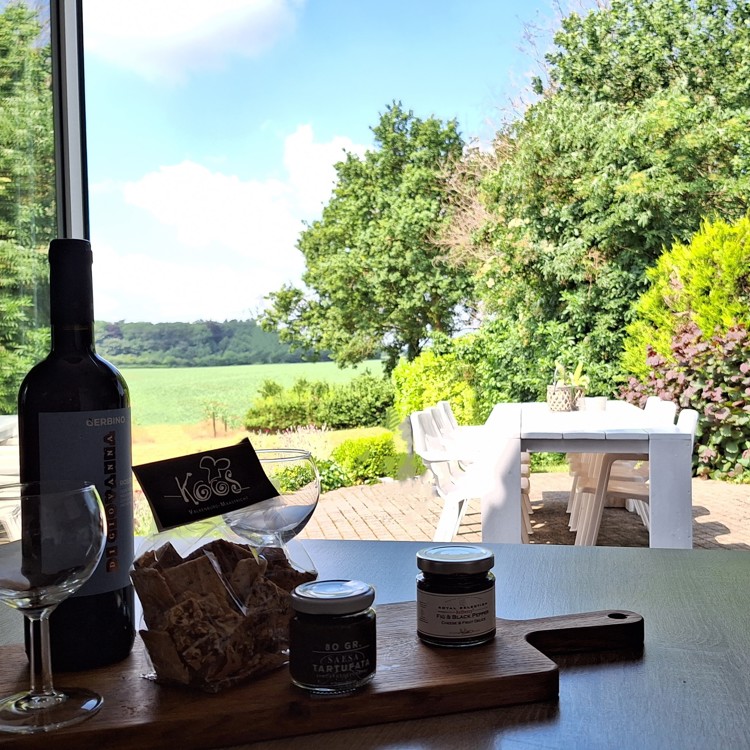 Uitzicht vanaf de dinertafel naar het terras en de tuin van groepsaccommodatie Domein Hellebeuk 