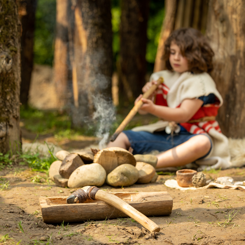 Prehistorisch jongetje is bezig met gereedschap en omringd door stenen