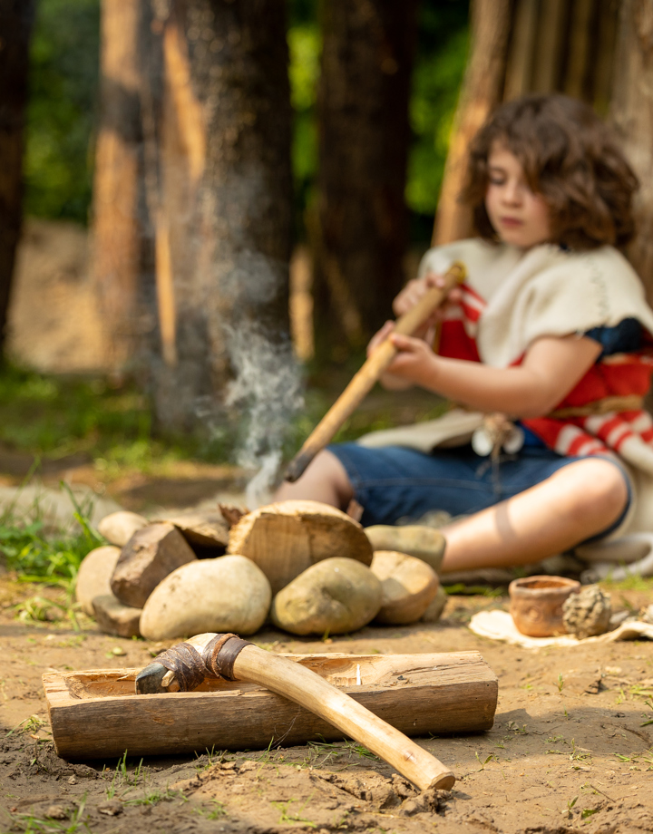 Prehistorisch jongetje is bezig met gereedschap en omringd door stenen