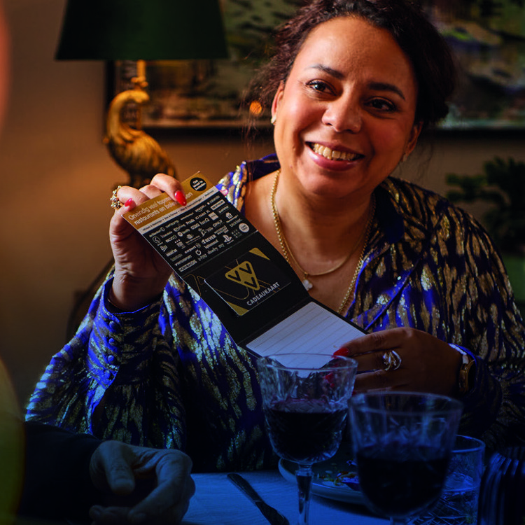 Een vrouw krijgt een goud deluxe VVV cadeaukaart cadeau van een vriendin