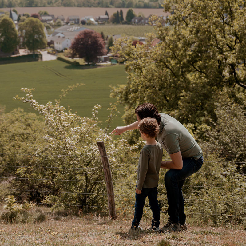 Vader en zoon op de Bemelerberg, vader wijst iets aan 