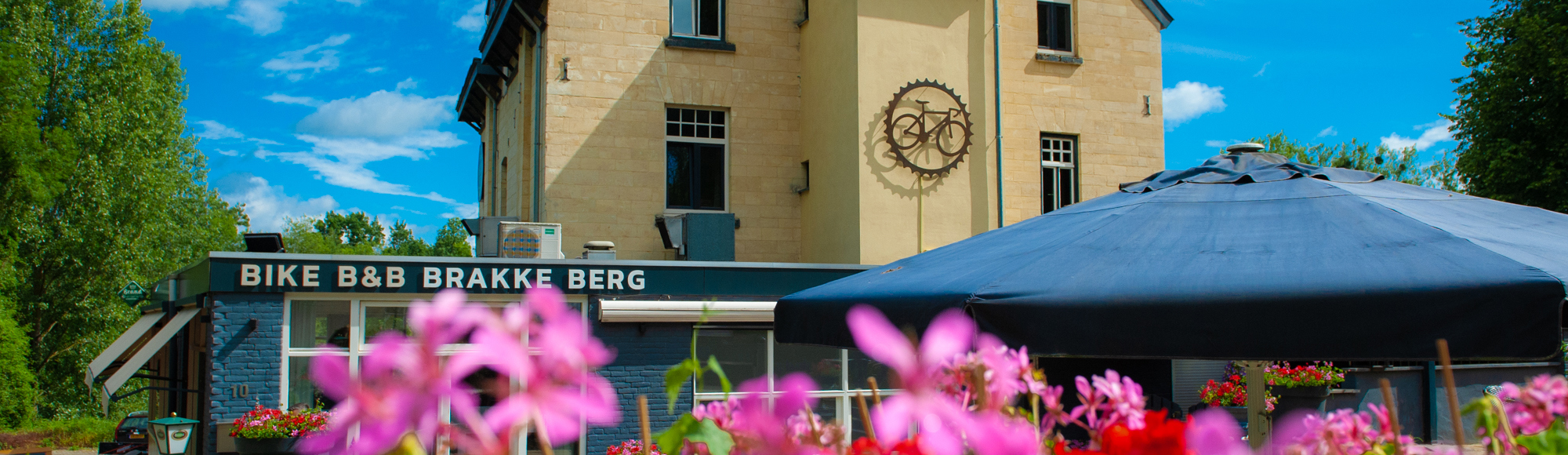 Hotel in mergelgebouw speciaal voor fietsers, met roze bloemetjes op de voorgrond. 