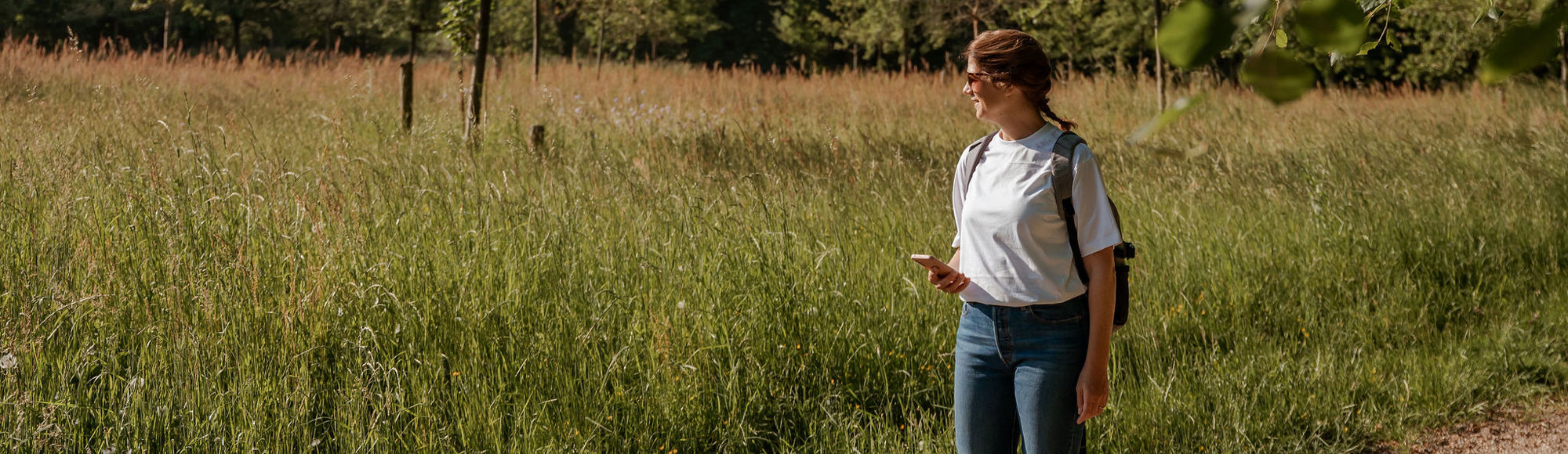Vrouw is alleen aan het wandelen in een weiland omgeven door bomen