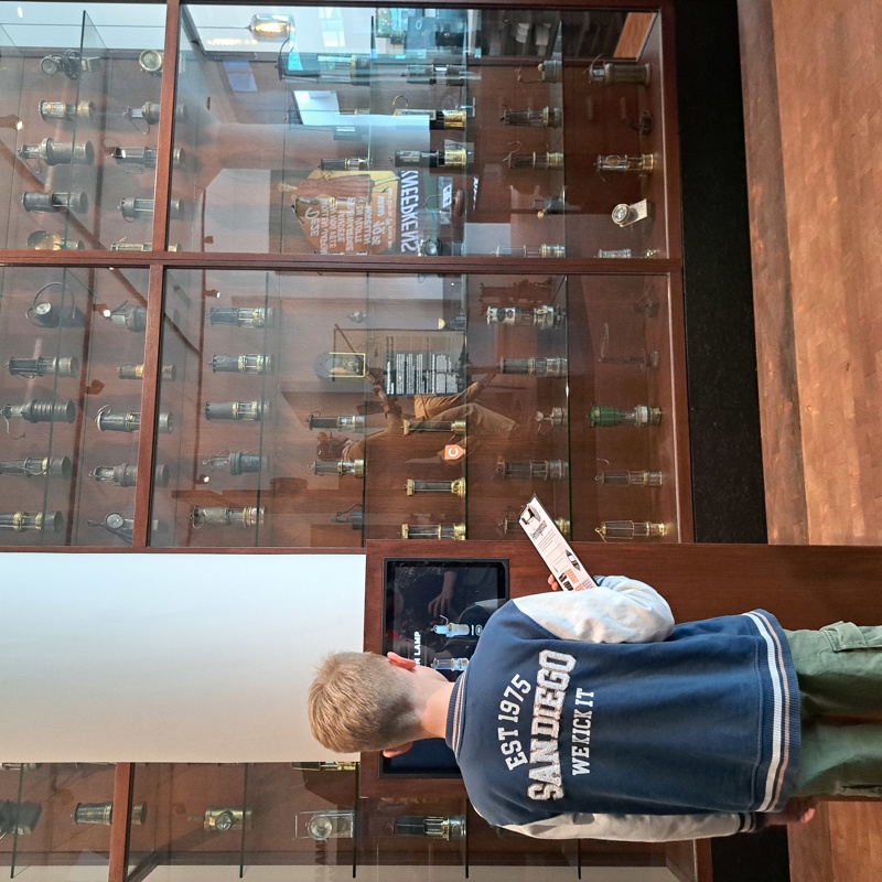 Jongen naar scherm kijkend met daarachter glazen vitrinekast