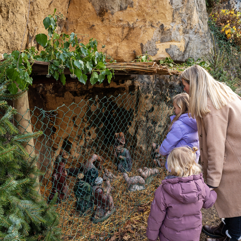 Moeder en dochter kijkend naar Kerstkribke in grot