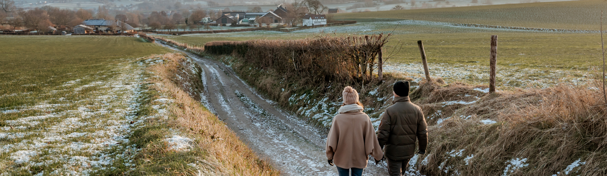 Twee mensen wandelend op pad met uitzicht op heuvels in de winter