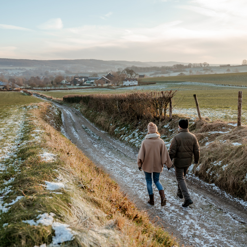 Twee mensen wandelend op pad met uitzicht op heuvels in de winter