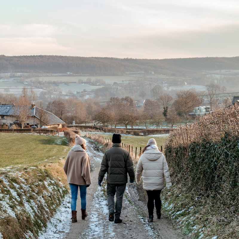 Panorama uitzicht over winterse heuvels met drie personen wandelend over pad