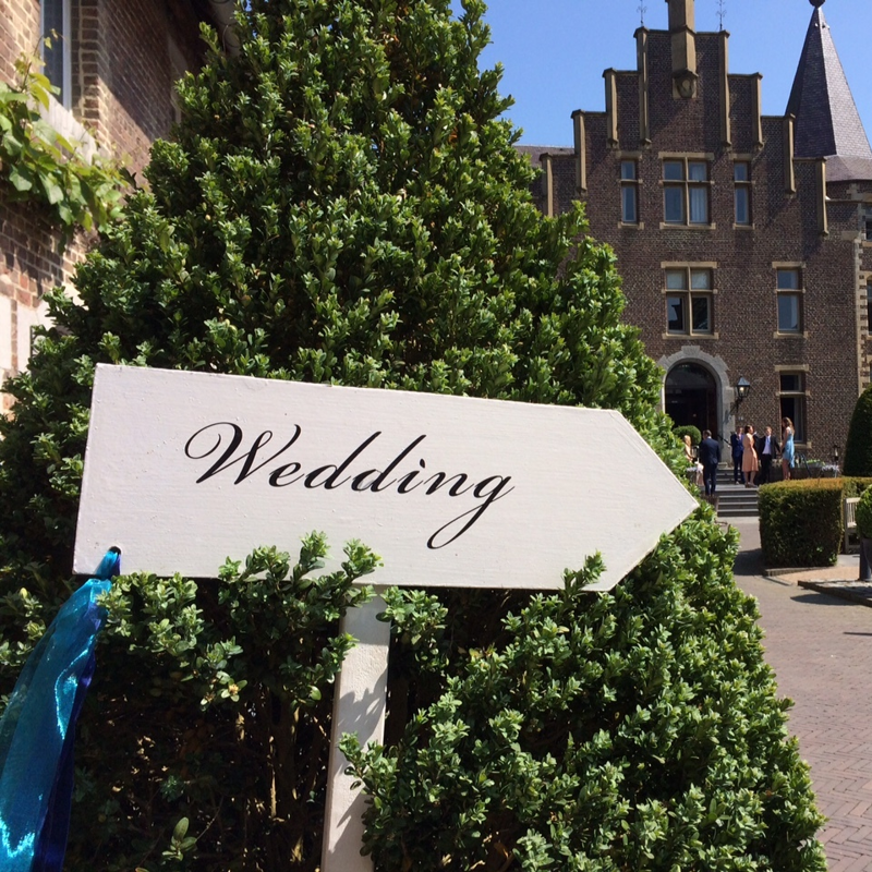 Wit "wedding" bordje met pijl naar rechts richting een kasteeltje wat dient als trouwlocatie. 