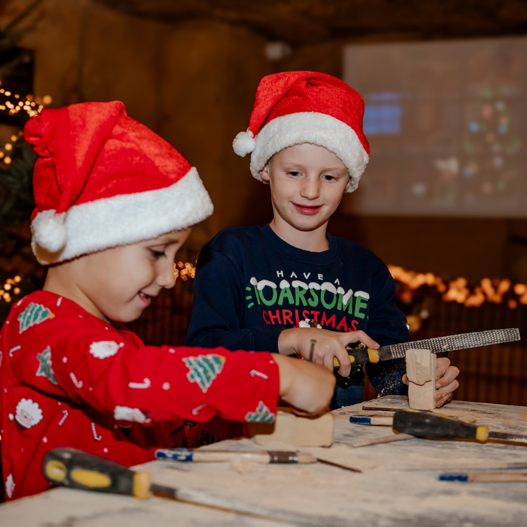 Twee kinderen met kerstmuts op en gereedschap met kerstverlichting