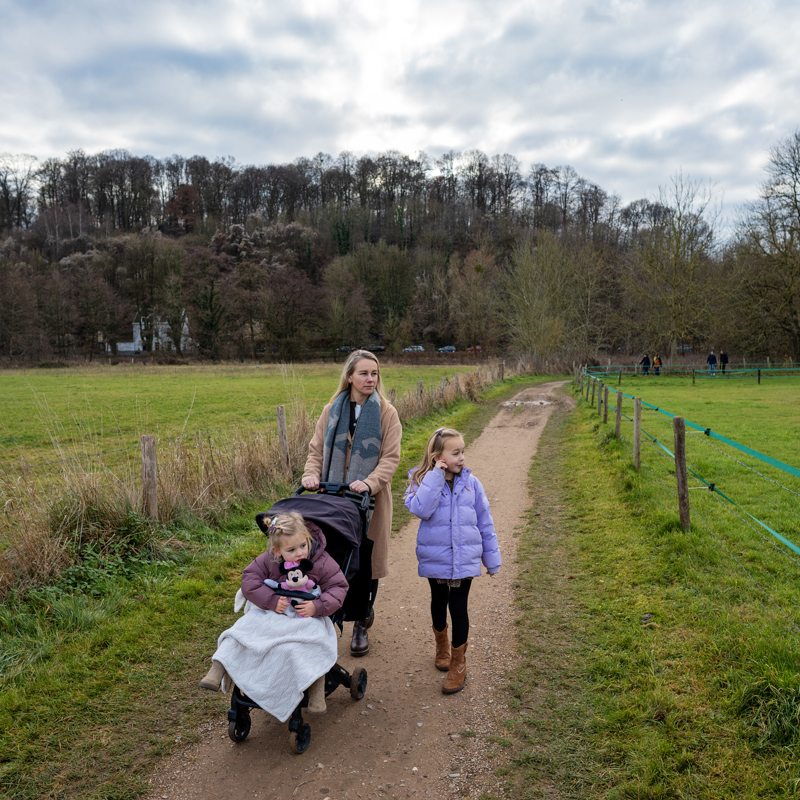 Moeder met kinderwagen wandelend over onverhard pad