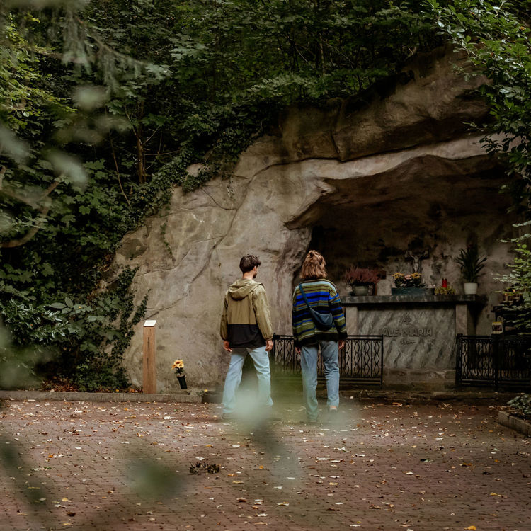 Twee mensen bij grot met natuur om hen heen