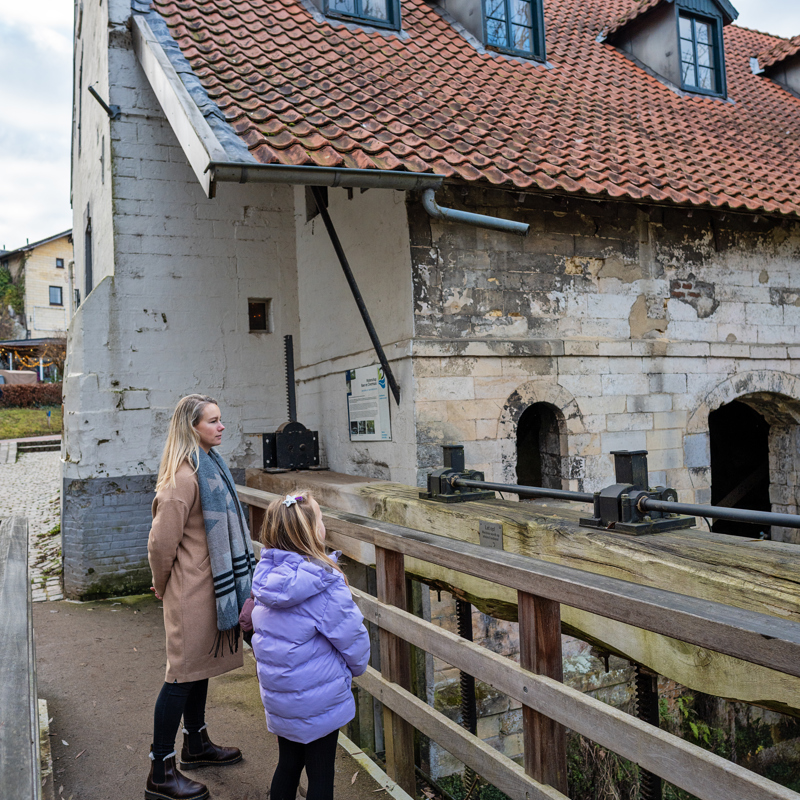Vrouw en kind op bruggetje kijkend naar stromend water