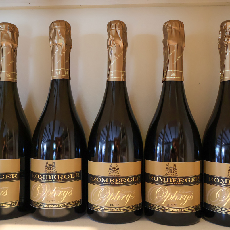 Een vijftal wijnflessen van wijngoed Fromberg met een goudkleurig etiket. 