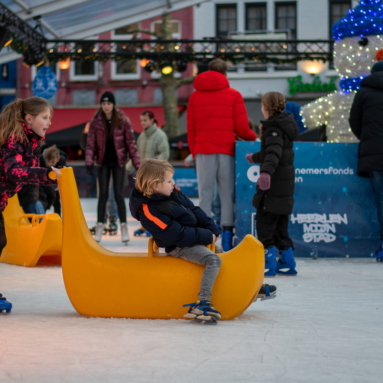 Twee kinderen schaatsend op ijsbaan met slee