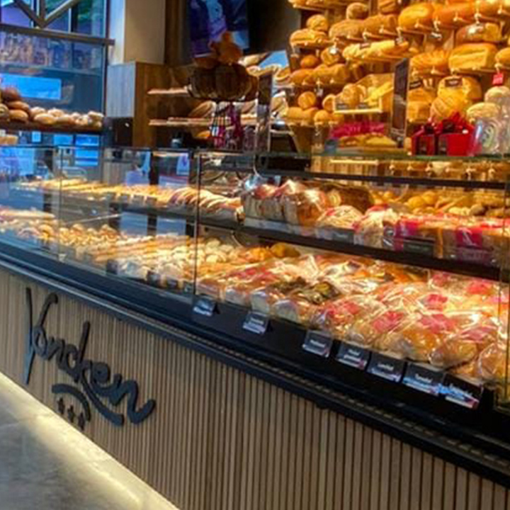 Vitrine in een bakkerij met een hoop broodjes en gebak achter het glas. 