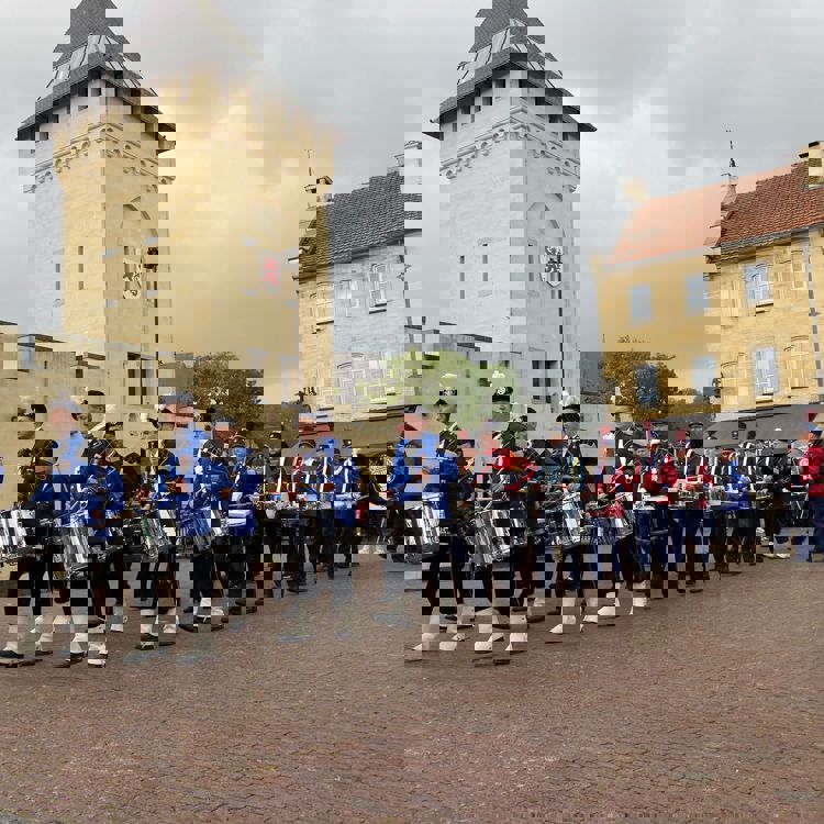 Muzikanten van verschillende harmoniën lopen in formatie voor de Geulpoort tijdens de Valkenburgse Bokkenweken