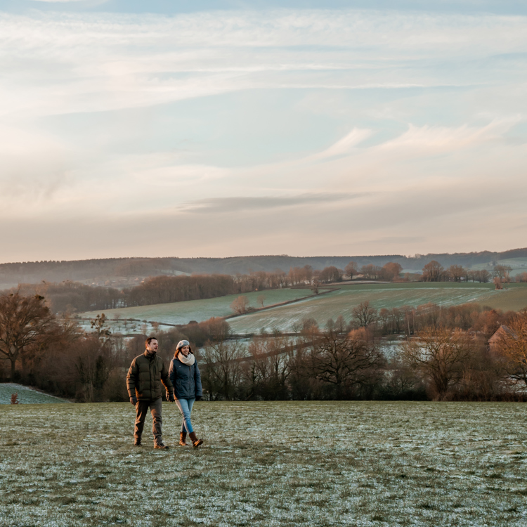 Twee mensen wandelend hand in hand door besneeuwd veld met uitzicht