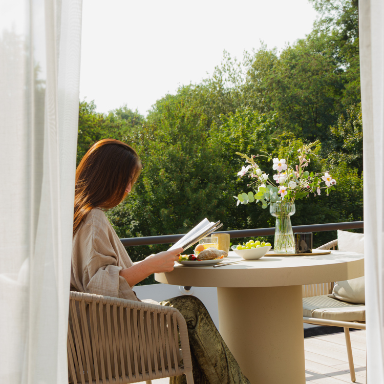Vrouw buiten aan tafel met krant en eten