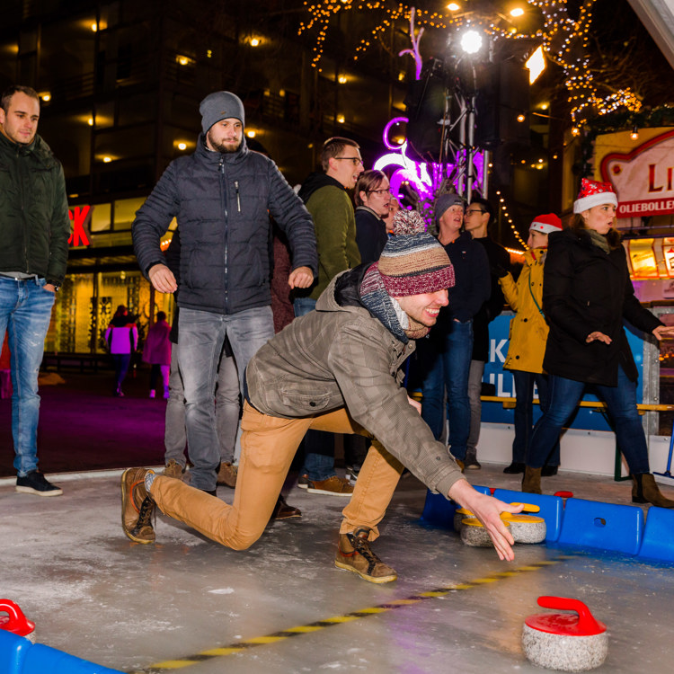 Man op Curlingbaan met curlingsteen op de baan