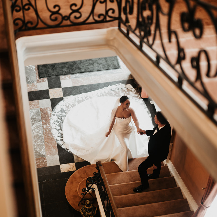 Bruidspaar in de gang onderaan de trap in een prachtig historisch kasteel. 