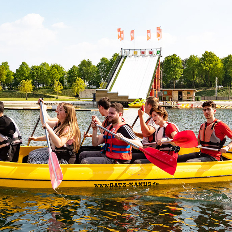 Grote gele kajak met een groep vrienden erin op natuurwater in limburg.