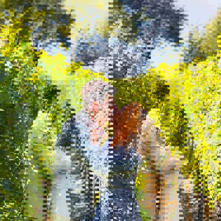 Bruidspaar geeft elkaar een kus tussen de wijnranken in zuid-limburg