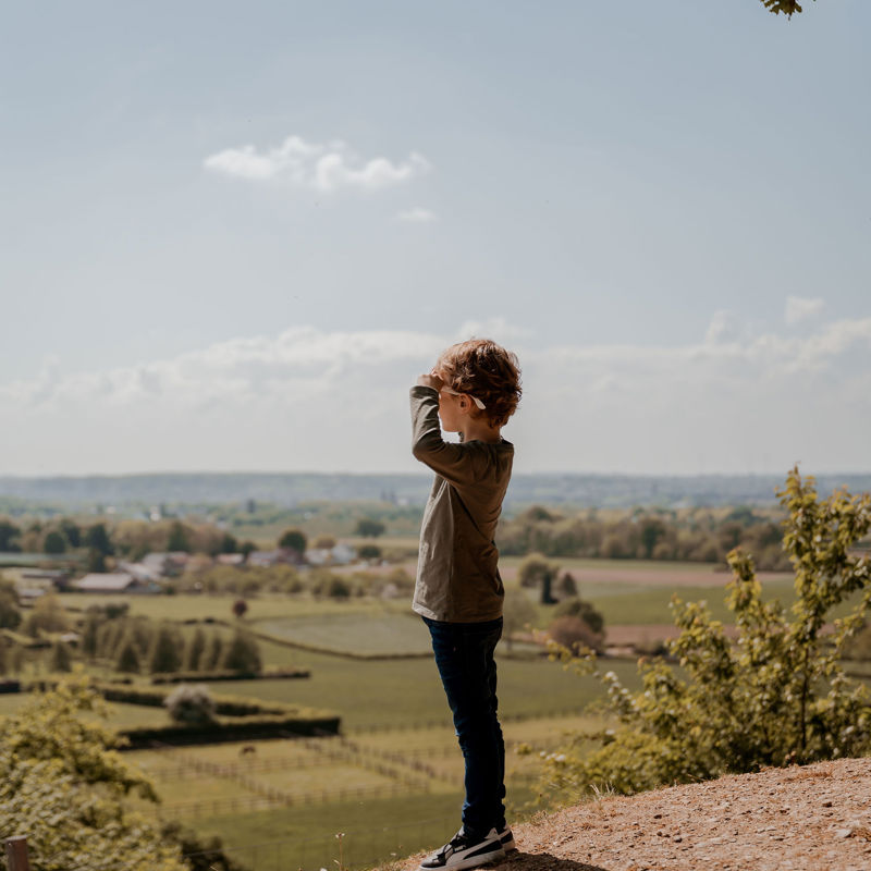Jongetje met zonnebril kijkt vanaf de Bemelerberg naar het uitzicht