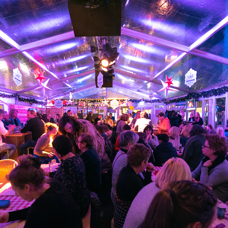 Grote groep mensen in overdekte hal met kerstverlichting