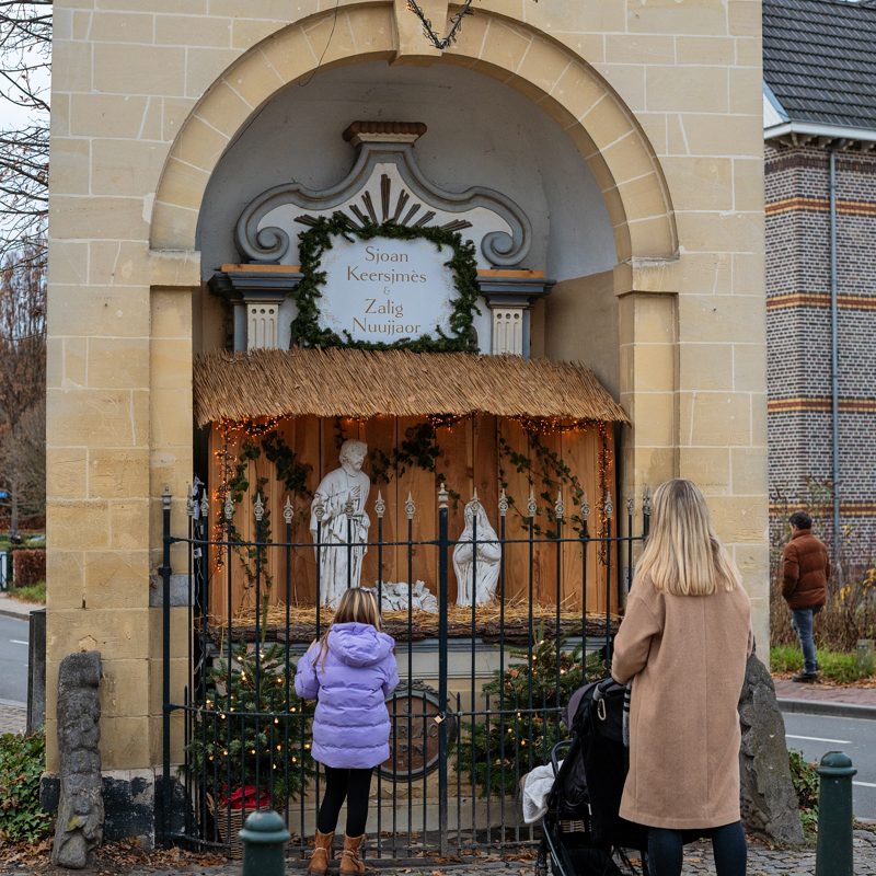 Vrouw met kinderen kijkend naar Kerstkribke Wandering Dutchies