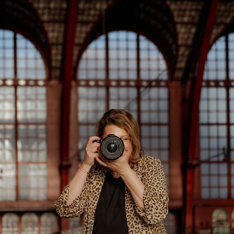 Fotografe sanne kijkt door de lens van haar camera in een oud gebouw